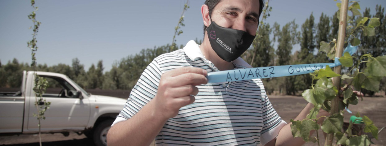 Primer plano de un hombre de unos 35 años con barbijo que muestra una cinta azul que está atada a una pequeña rama en la cinta azul se puede leer Álvarez Guillermo al fondo se ve parte de una camioneta blanca.